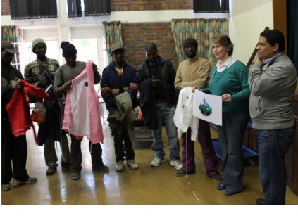 Mary Gillett-de Klerk holds the Josh poster while some of the homeless people admire their clothes that were given by her, next to Mary is Andrew Hendricks of the Ferndale Bible Chapel at  the launch of the voucher scheme at the Randburg Methodist Church, on the Mandela Day.