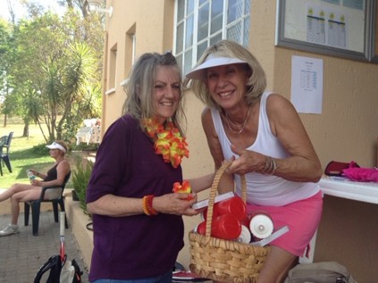 Lynn Munroe is presented with a spot prize for her Spring flowers on her tekkies and around her neck, by Olivedale Tennis Club Committee Member Jackie Farnell